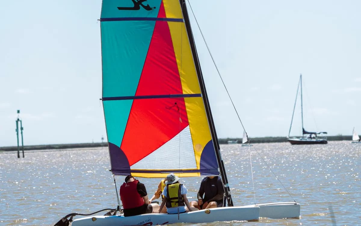 Un catamarán de velas de colores navega con su tripulación