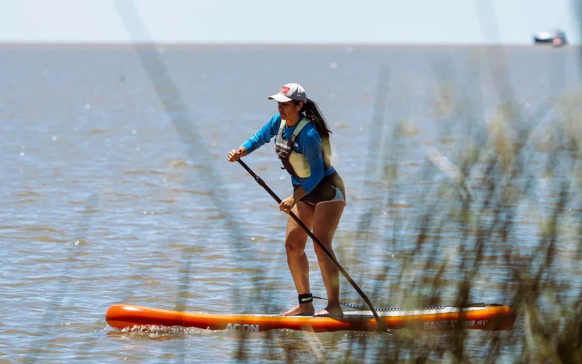 Una remadora de pie sobre una tabla de SUP en el río